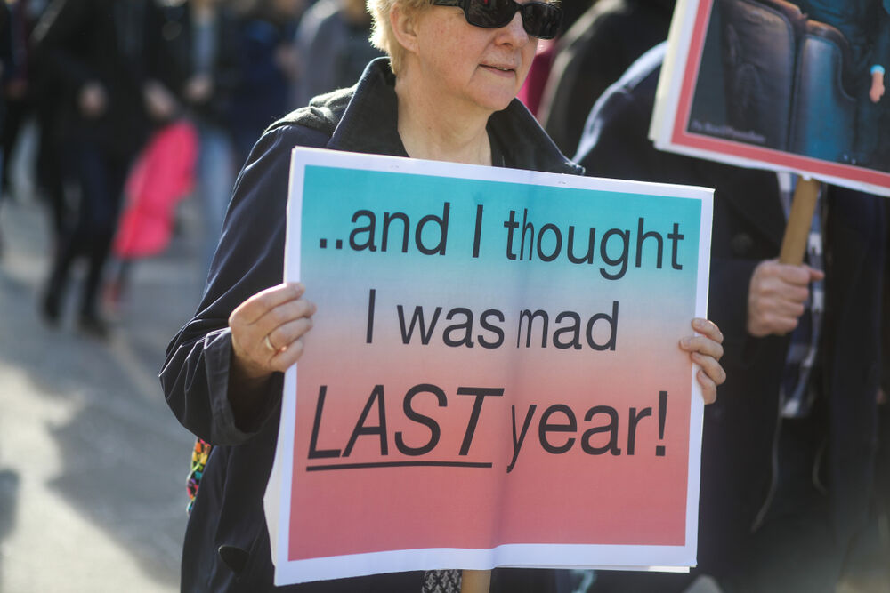 Woman holding a sign that reads, "And I thought I was mad last year"