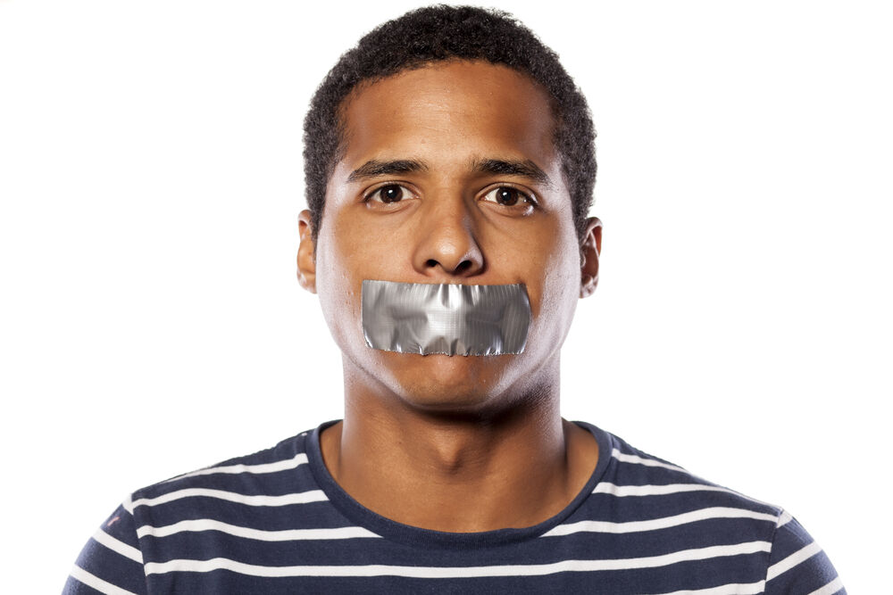 A person with tape on their mouth, symbolizing being unable to speak