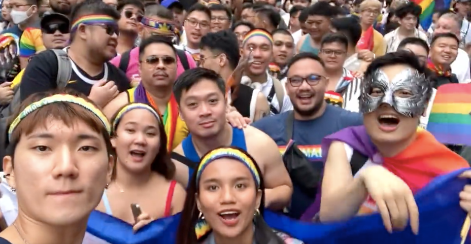A crowd of young Taiwanese people wearing rainbow flags stands at the 2023 Taiwan Pride parade.