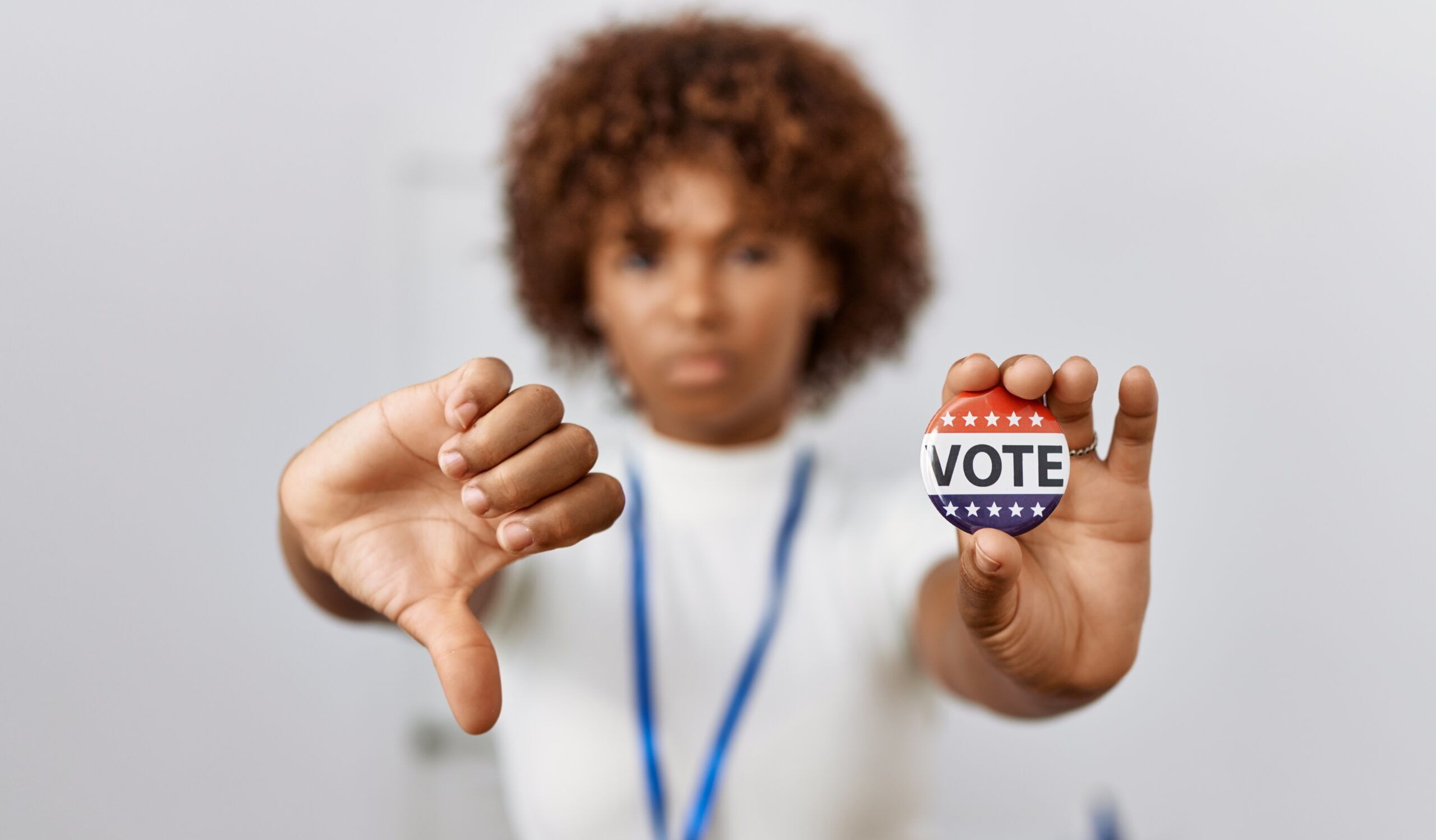Young african american woman at political campaign election holding usa badge with angry face, negative sign showing dislike with thumbs down