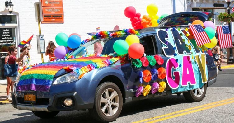 Babylon, New York, USA - 5 June 2022: Gay Pride car parade travelling down Deer Park Ave in Babylon Village with people waving rainbow flags and celebrating diversity.