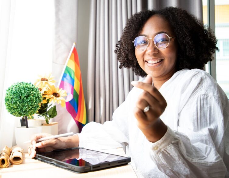 Africa American lesbian, Beautiful gay working on tablet with love moment spending good time together, lgbt rainbow, pride flag on table near curtain at window. kosa-lgbtq-teens-censorship-social-media-problems-fixing
