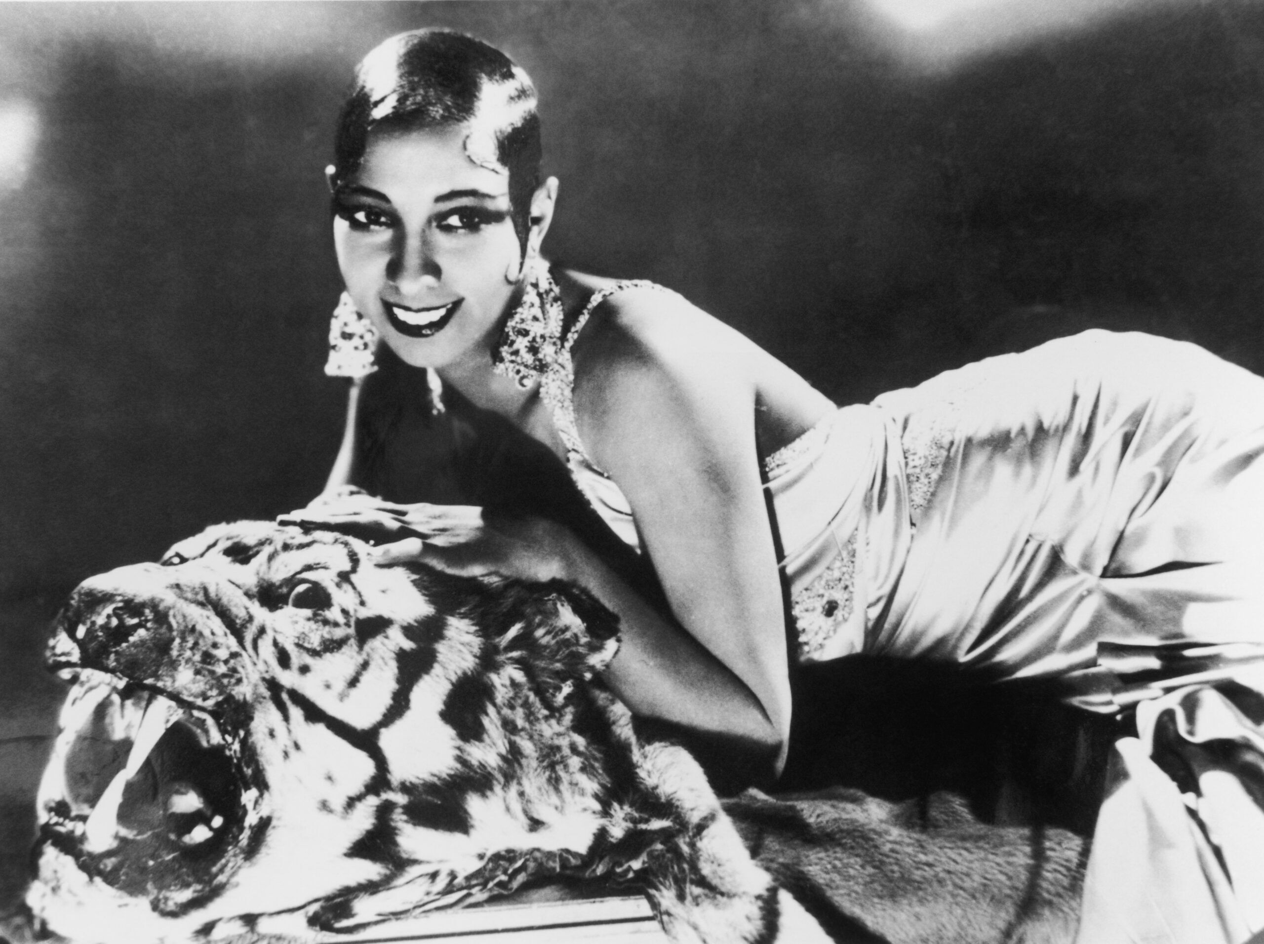 circa 1925: Portrait of American-born singer and dancer Josephine Baker (1906 - 1975) lying on a tiger rug in a silk evening gown and diamond earrings. (Photo by Hulton Archive/Getty Images)