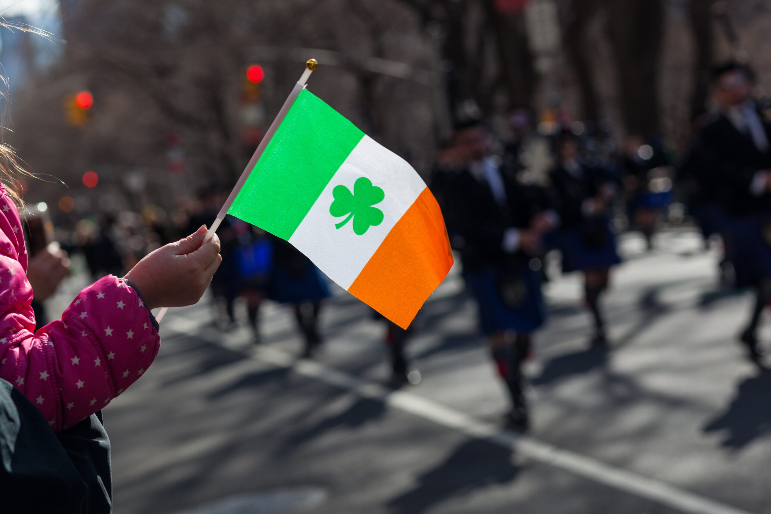 Child waves Irish flag while watching a St. Patricks Day Parade