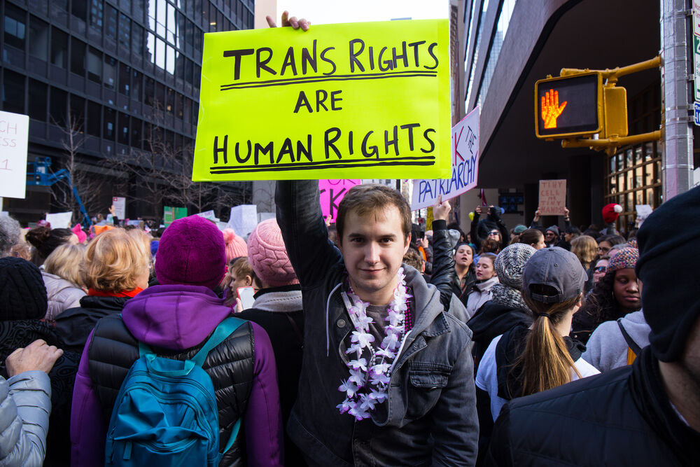A person protesting with a "trans rights are human rights" sign