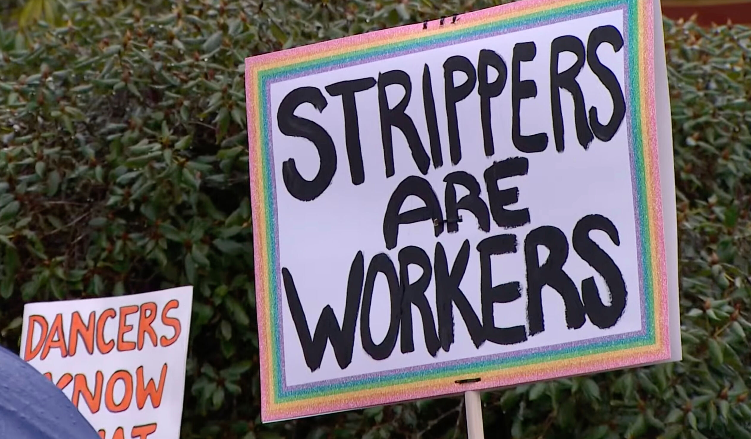Strippers and members of the LGBTQ+ community held signs and chanted outside the Washington state Capital in Olympia Monday.