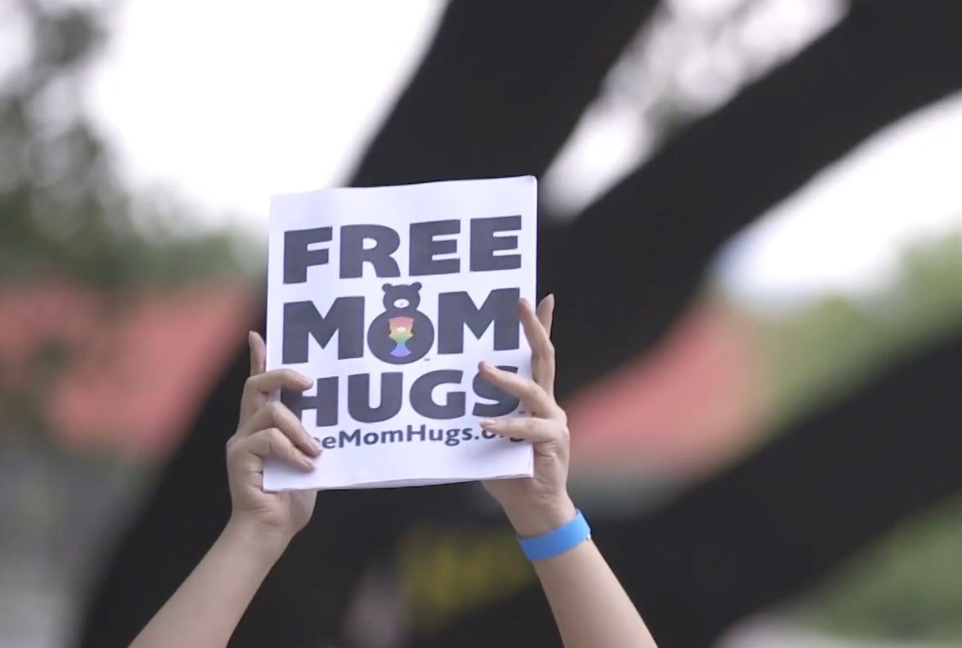 Free Mom Hugs volunteer holding up a "Free Mom Hugs" sign