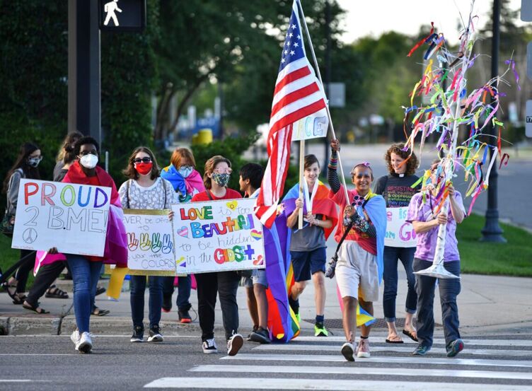 People hold signs as they cross Minnesota Highway 23 during the Community Pride and Peace Walk Tuesday, Sept. 14, 2021, in St. Cloud.
