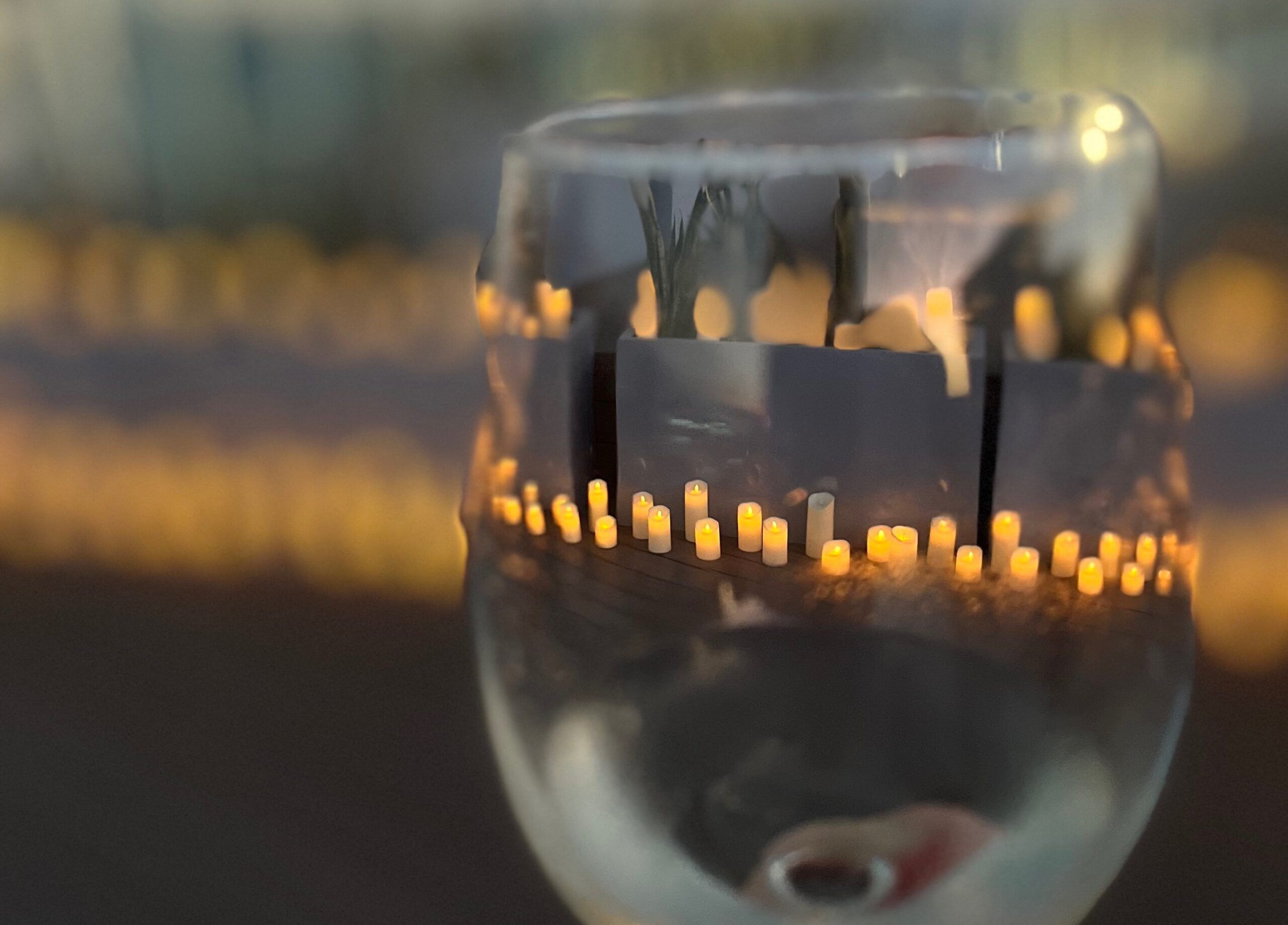 Wine glass showing candles through it