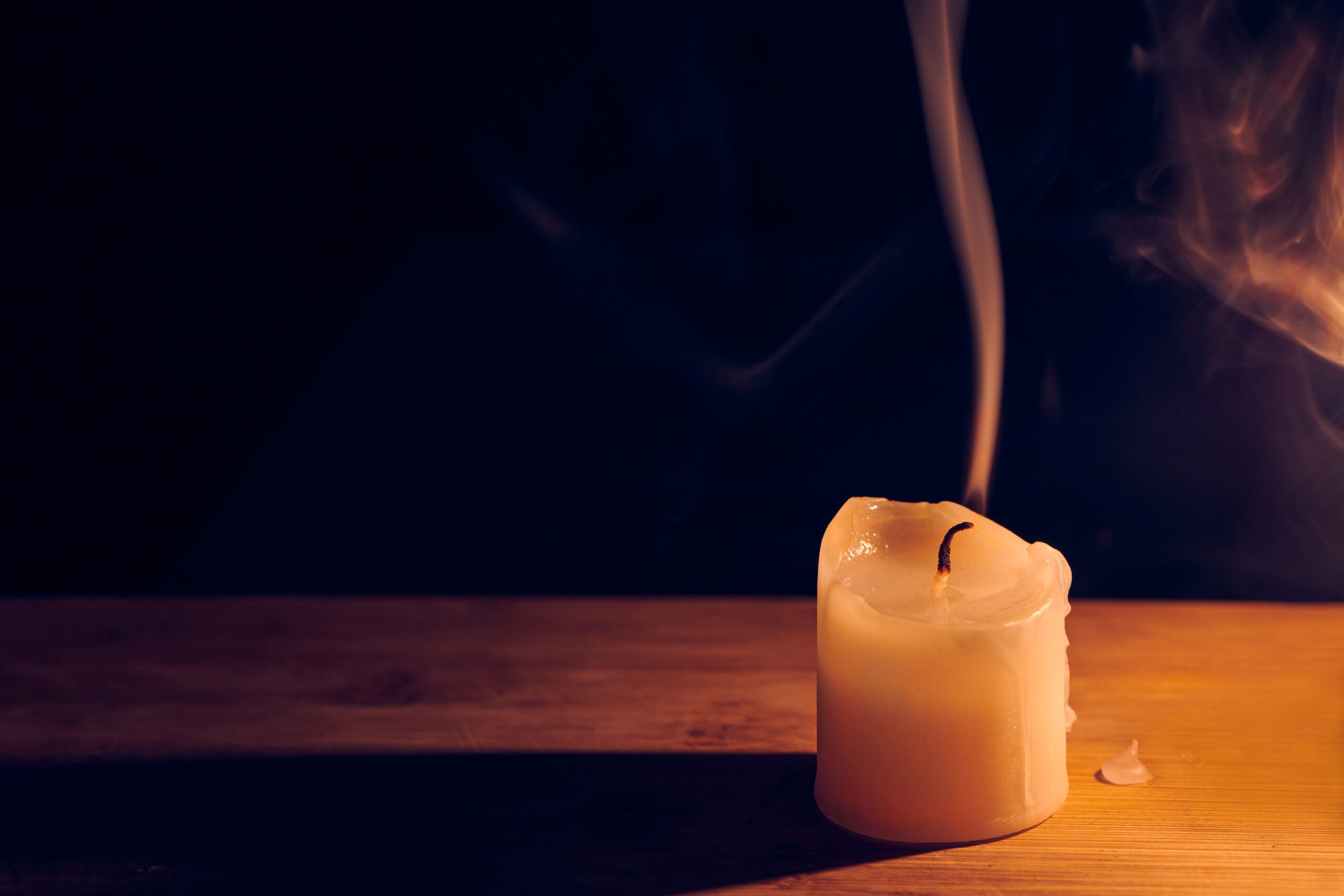 Smooth, white beautiful smoke from candle. Extinguished candle on wooden table. Close up view with copy space.