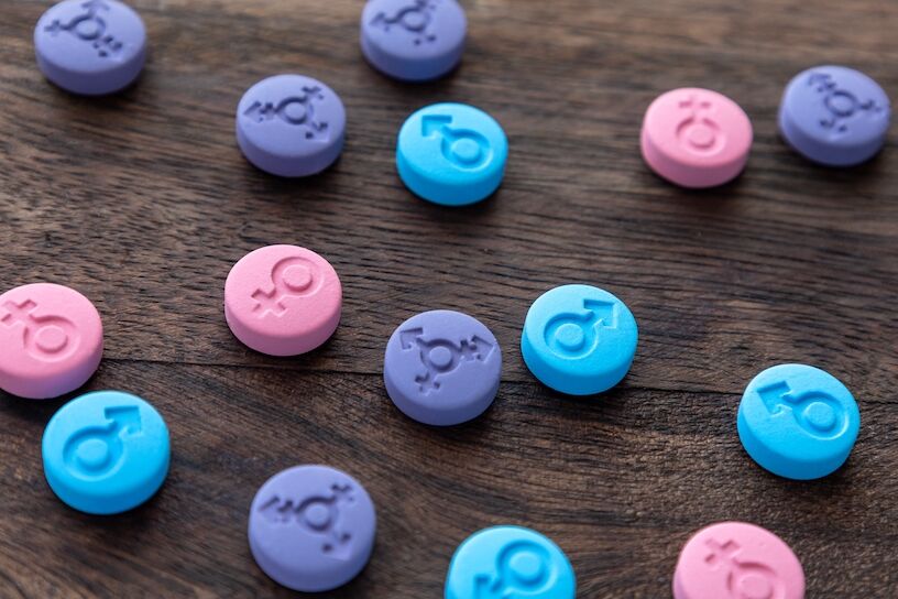 Hormonal pills. Gender symbols of man, woman and transgender. Colored tablets of blue, pink and purple color.