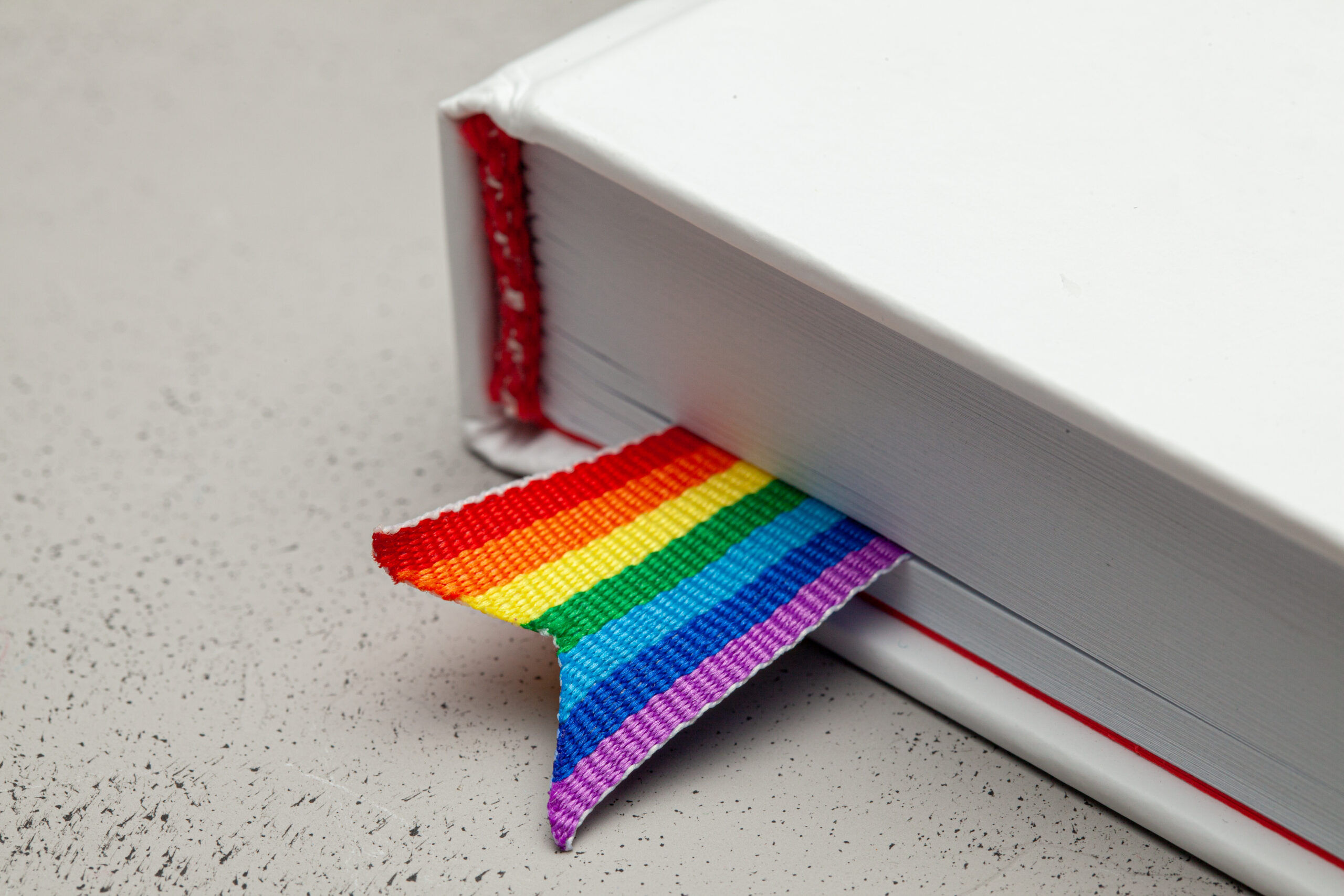 Book with bookmark and rainbow ribbon of LGBT pride.