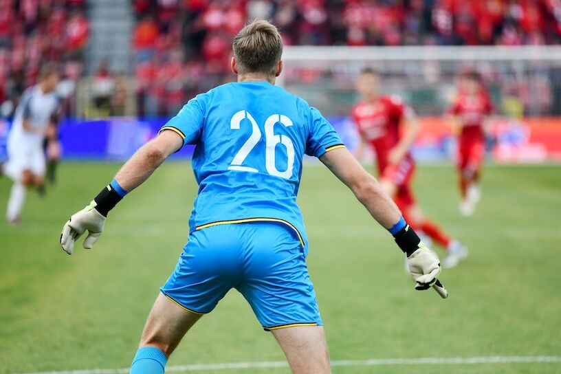 Goalkeeper back's and soccer match in the background