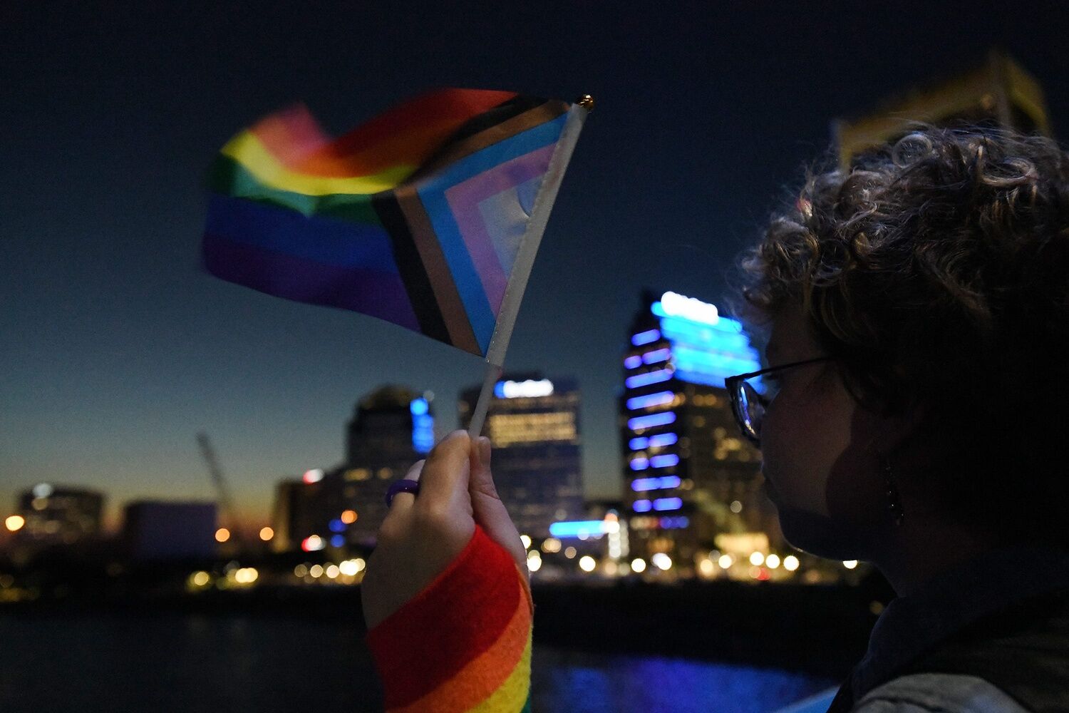 Clover Anglin holds a small LGBTQ+ flag as he takes his position on the Main Street Bridge in Jacksonville, Florida in preparation of lighting the bridge in pride rainbow colors on May 31, 2024.