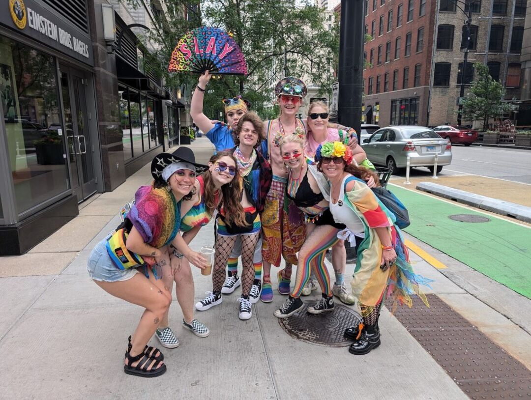 A crowd of happy Chicago Pride goers poses and smiles on the sidewalk after John Hall's MAGA prank