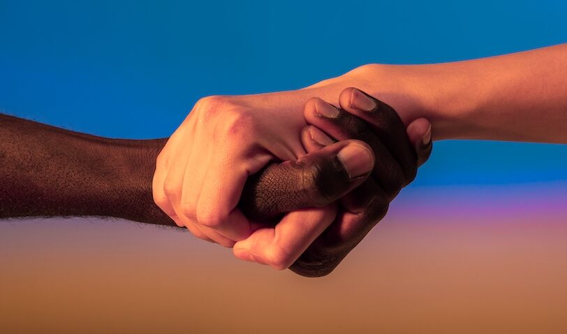 Close up multiracial woman couple with black and caucasian hands holding each other wrist in tolerance unity love and anti racism concept