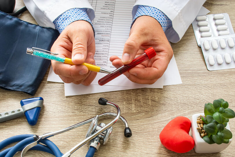 Doctor during consultation held in his hand and shows patient laboratory tube with blood. Counseling of transfusion, blood and hematologic diseases and pathology like anemias, cell cancer, hemophilia