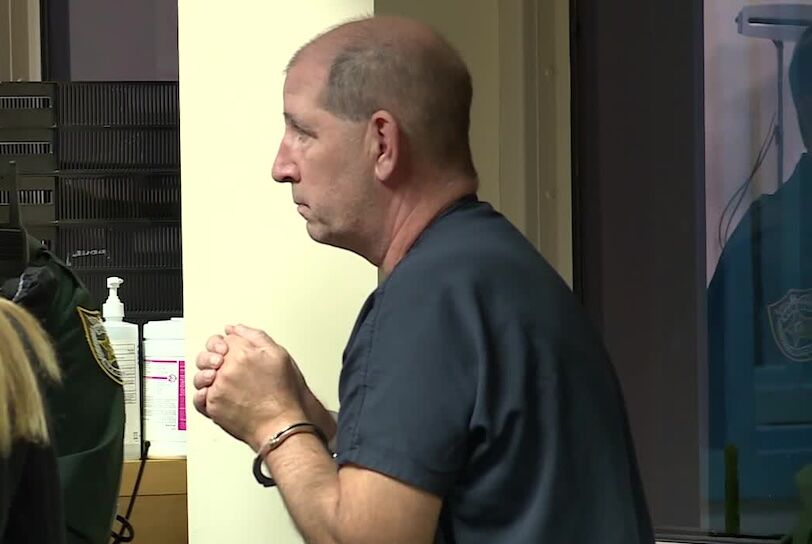 George Bereska in handcuffs at a police station.