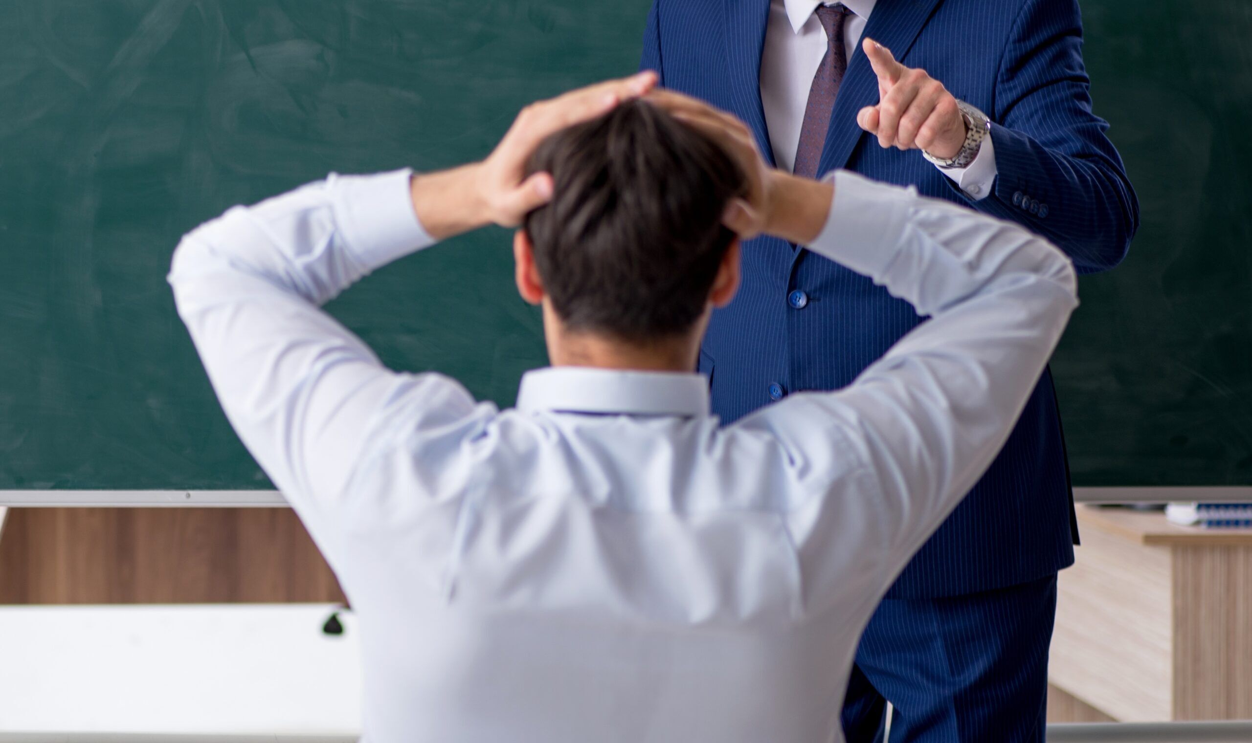 Old male teacher and young male student in front of green board