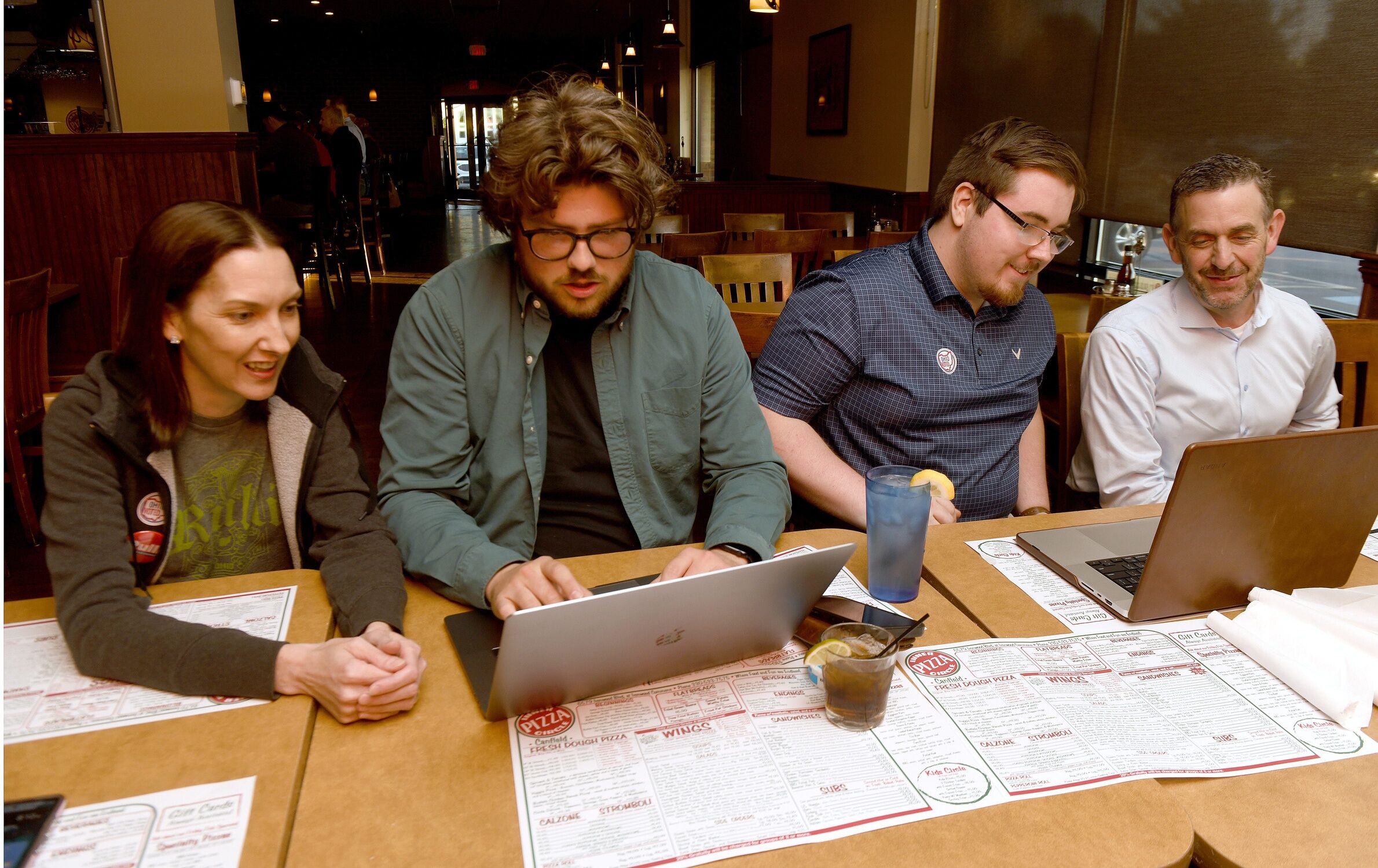 Sonia Kennedy and Tex Fischer (second from left) look over a computer at Inner Circle Pizza in Canfield with as results begin to come in for a special election. Tuesday, June 11, 2024.