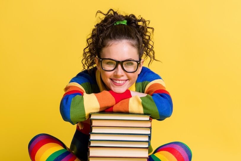 Photo of diligent student lady sitting floor lean book pile legs crossed wear striped rainbow clothes isolated yellow color background