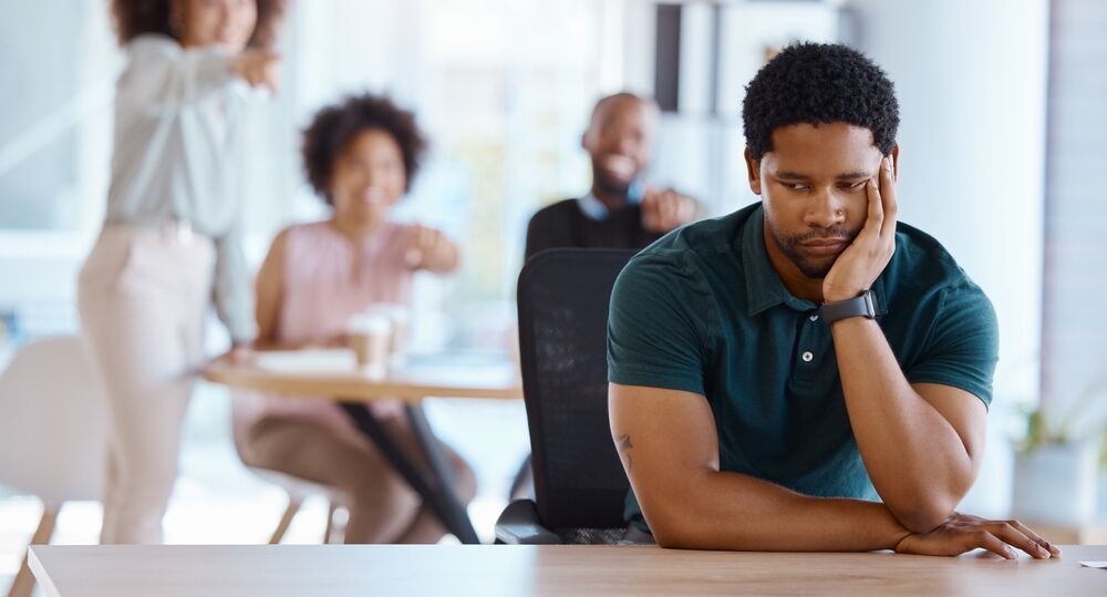 A sad man at the workplace, perhaps the victim of workplace discrimination