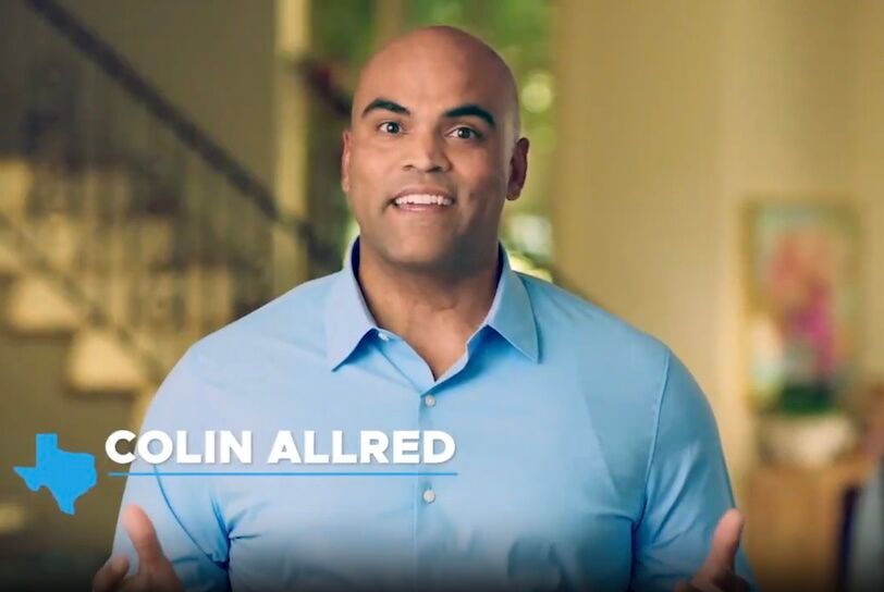 Rep. Colin Allred is a bald Black man in a blue collared shirt speaking indoors.