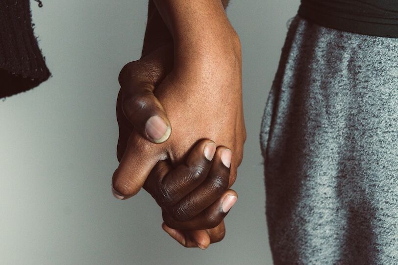 African Gay, LGBT and homosexuality concept - close up of happy lesbian gay couple holding hands for love and friendship concept