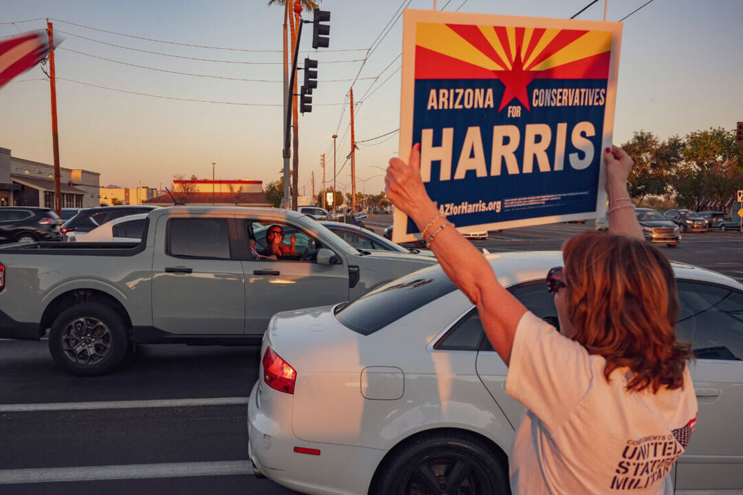 An Arizona resident holds a campaign sign that reads "Arizona Conservatives for Harris"