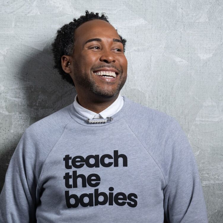 David Johns wearing a grey sweatshirt that reads, "Teach the Babies."