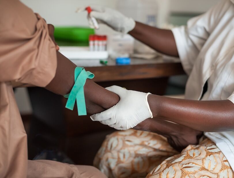 African nurse is drawing blood from an African male for blood tests.