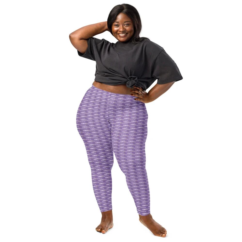A female-presenting person posing confidently while wearing light purple all-over print LGBTQ Nation leggings and an oversized black t-shirt tied at the waist