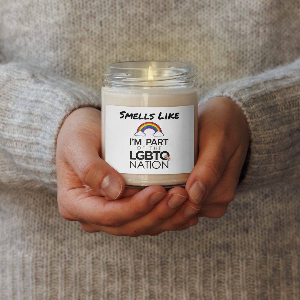 a person wearing a cozy sweater holding a “Smells Like I’m Part of the LGBTQ Nation” Candle with both hands