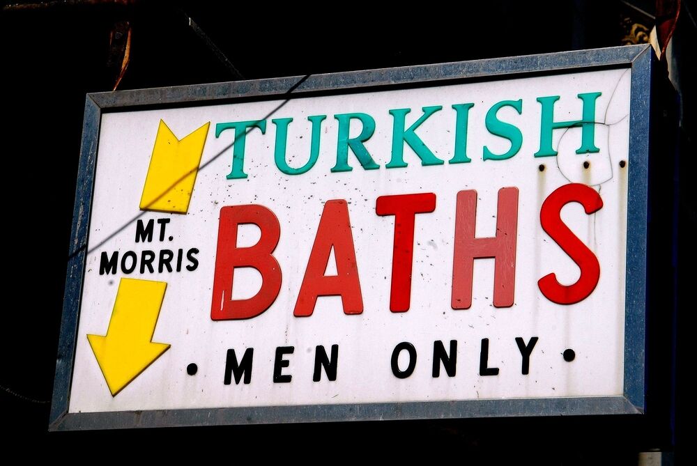 The sign says St. Morris Turkish Baths, men only, and has a yellow arrow pointing downward