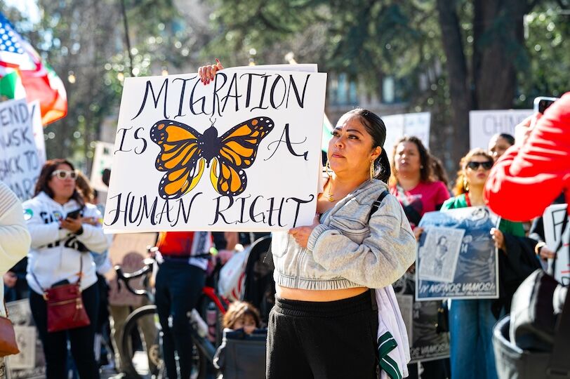 Sacramento, CA, U.S.A. - Feb. 22, 2025: A woman holds up a sign about migration being a human right at the Pro-immigrant Protest in downtown at Cesar Chavez park.