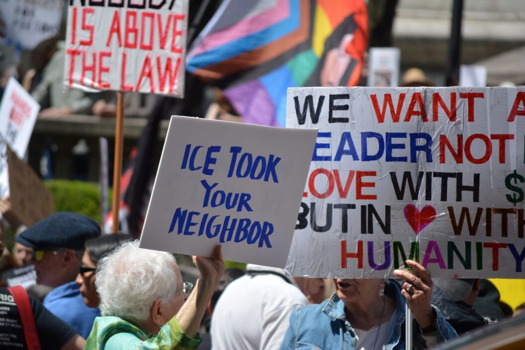People holding signs at an Anti-Trump protest against the current administration's actions on immigration and civil rights in Midtown Manhattan.