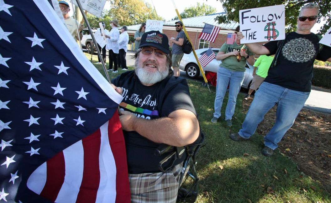 Kenny Gay holds the flag as he joined hundreds of No Kings Day protesters who lined up on both sides of Wilkinson Boulevard near Main Street Crossing in Belmont Saturday afternoon, Oct. 18, 2025.